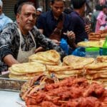 A street vendor sells traditional Bangladeshi snacks in a busy Dhaka market.