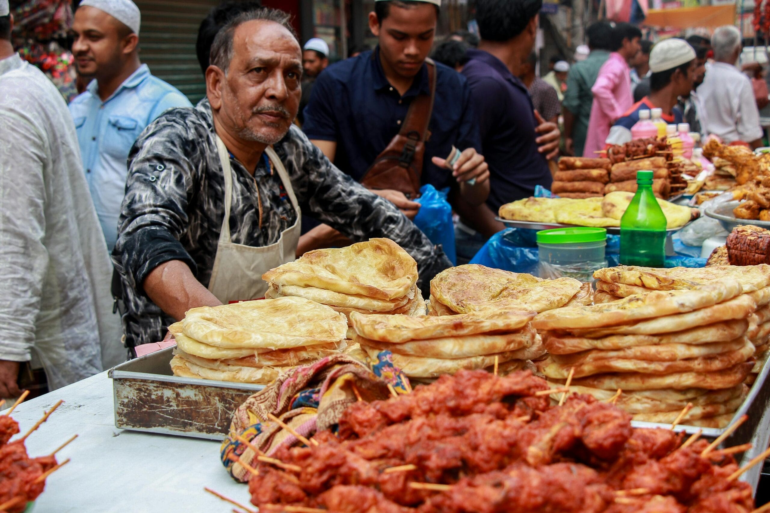A street vendor sells traditional Bangladeshi snacks in a busy Dhaka market.