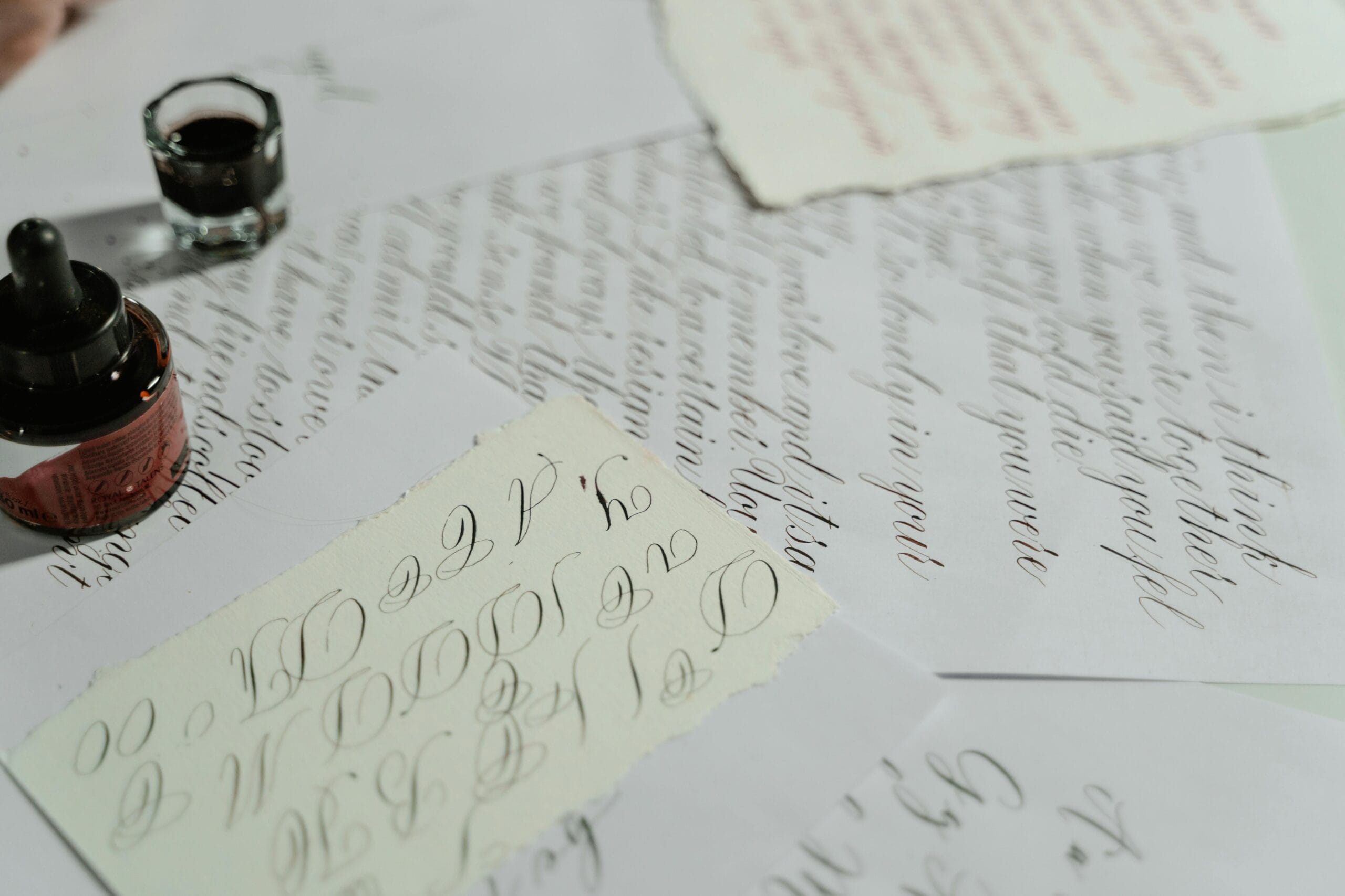 A detailed view of intricate calligraphy writing on white sheets with ink bottle.