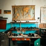 A cluttered workshop desk with vintage tools and a world map on the wall.