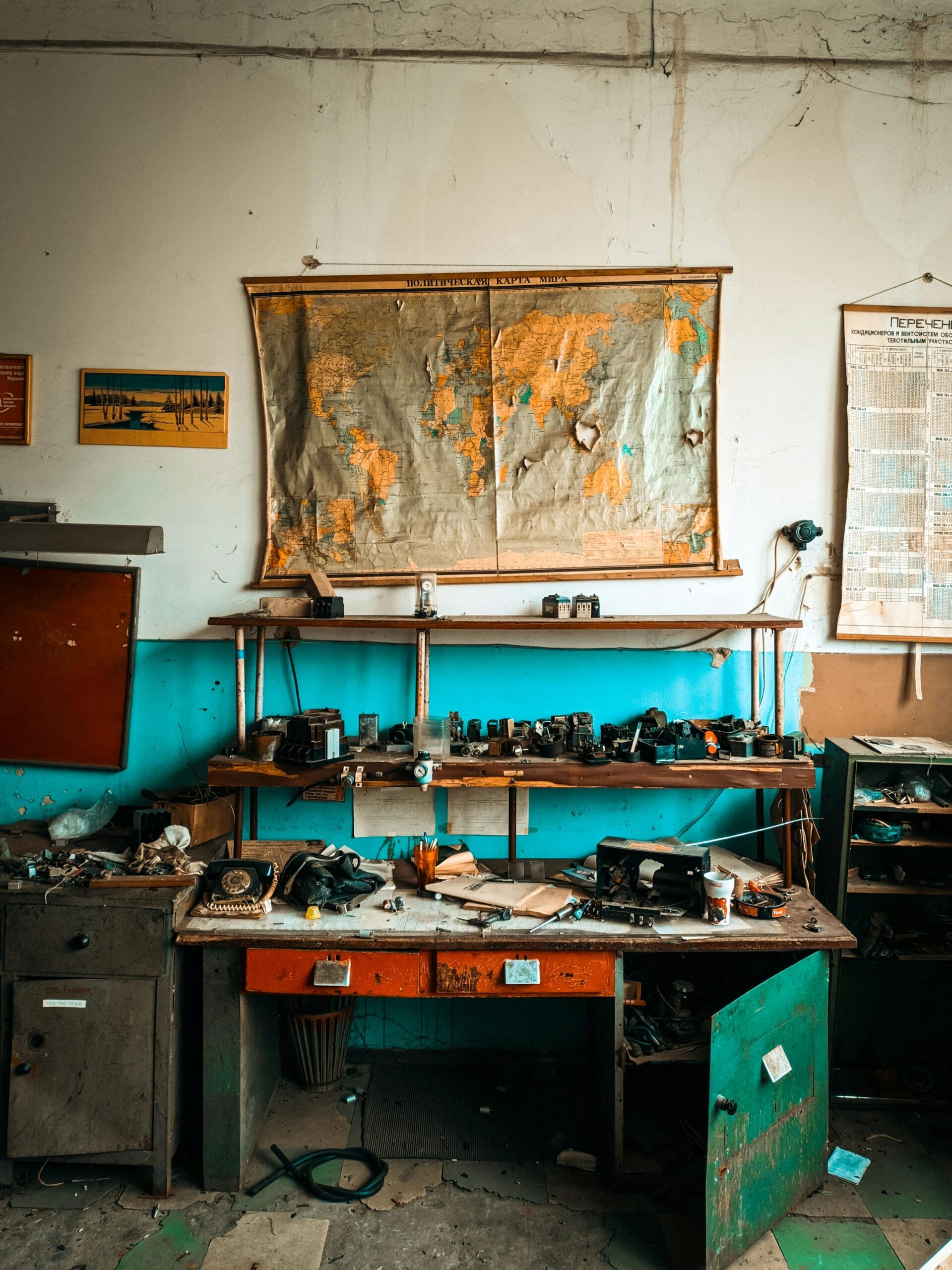 A cluttered workshop desk with vintage tools and a world map on the wall.